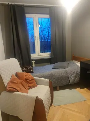 a bedroom with two beds and a chair and a window at u cioci Lutki urocze mieszkanie z balkonem in Kraków