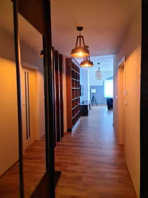 a hallway with wood floors and a hallway with bookshelves at Apartament Limanowa Rynek in Limanowa
