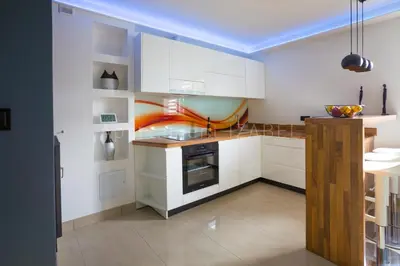 a kitchen with white cabinets and an orange stripe on the wall at Apartament Izabel in Nowy Targ