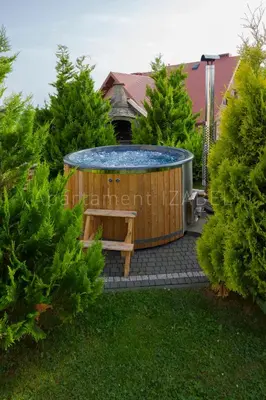 a hot tub in a yard with a bench and trees at Apartament Izabel in Nowy Targ