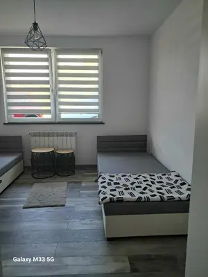 a bedroom with two beds and two tables and two windows at Apartament Izabel in Nowy Targ