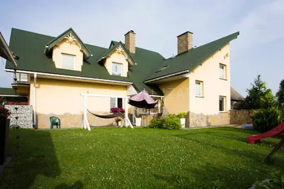 a house with a hammock in the yard at Apartament Izabel in Nowy Targ