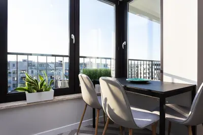 a dining room with a table and chairs and windows at City of the Kings - Indigo Apartment in Kraków