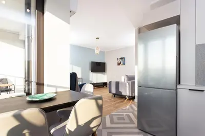 a kitchen and dining room with a table and a refrigerator at City of the Kings - Indigo Apartment in Kraków