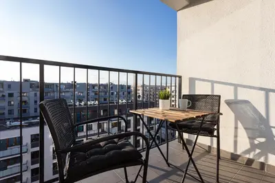a balcony with a table and chairs on a building at City of the Kings - Indigo Apartment in Kraków