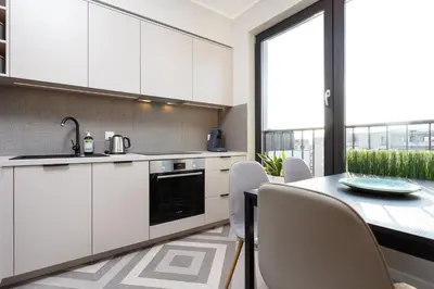 a kitchen with white cabinets and a table with chairs at City of the Kings - Indigo Apartment in Kraków