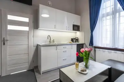 a kitchen with white cabinets and a table with flowers at DAVE Elegant Apartments KRAKÓW Old Town in Kraków