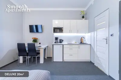 a kitchen with white cabinets and a table and chairs at SMOOTH Elegant Apartments KRAKÓW Old Town in Kraków