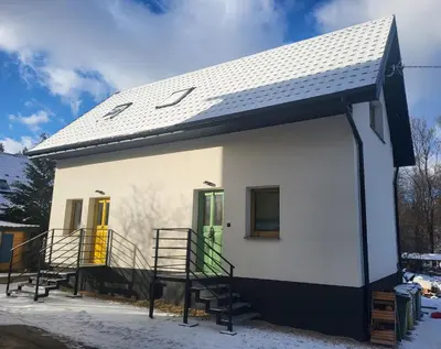 a small white house with a black roof at Slow Life Rabka in Rabka