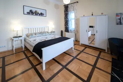 a bedroom with a white bed and a wooden floor at Apartament Moments Stare Miasto Style and Comfort Netflix in Kraków