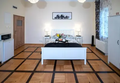 a bedroom with a white bed and a wooden floor at Apartament Moments Stare Miasto Style and Comfort Netflix in Kraków
