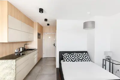 a kitchen with white cabinets and a bed in a room at Apartamenty Platinex 5 in Kraków