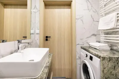 a bathroom with a sink and a washing machine at Apartamenty Platinex 5 in Kraków