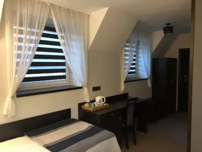 a bedroom with a bed and a desk and windows at Zajazd Podzamcze in Olkusz