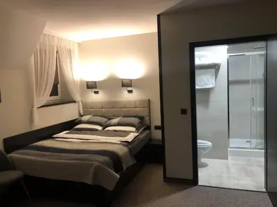a bedroom with a bed and a bathroom with a shower at Zajazd Podzamcze in Olkusz