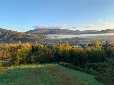 an aerial view of a field with fog in the hills at Apartamenty Pod Kątami in Kamienica