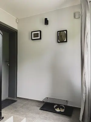 a room with a white wall with three pictures and shoes on it at Apartamenty Pod Kątami in Kamienica