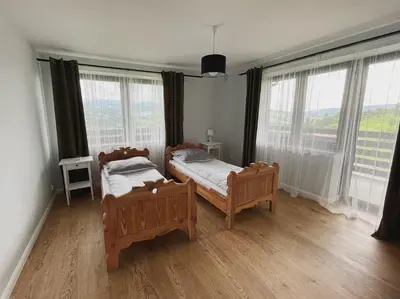 two beds in a room with large windows at Apartamenty Pod Kątami in Kamienica