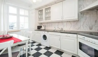 a white kitchen with a sink and a washing machine at Apartment Świetego Tomasza in Kraków