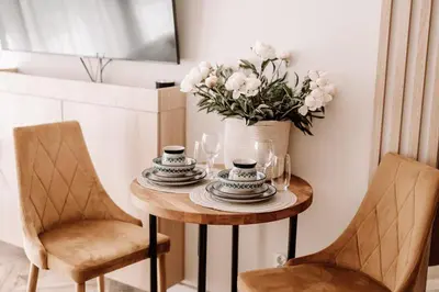a table with two chairs and a vase with flowers at Partnerapart Rakowicka 14 in Kraków
