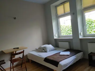 a small bedroom with a bed and two windows at 999 Aparthostel in Kraków