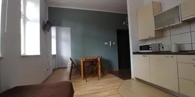 a kitchen with white cabinets and a table in a room at 999 Aparthostel in Kraków