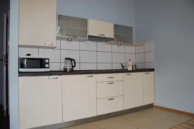 a kitchen with white cabinets and a microwave at 999 Aparthostel in Kraków