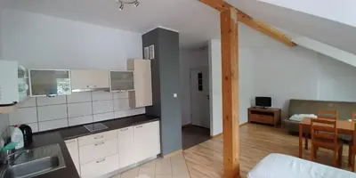 a kitchen with white cabinets and a dining room at 999 Aparthostel in Kraków