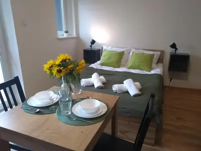 a room with a table and a bed with green pillows at Orange Apartament in Wadowice
