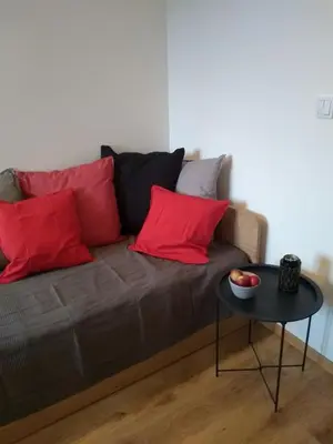 a brown couch with red pillows and a table at Orange Apartament in Wadowice