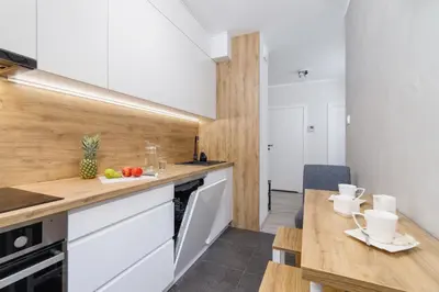 a kitchen with white cabinets and a wooden counter top at W Parku Lotników Apartments Tauron Arena by Noclegi Renters in Kraków