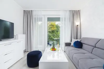 a living room with a couch and a table and a tv at W Parku Lotników Apartments Tauron Arena by Noclegi Renters in Kraków