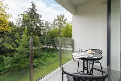 a balcony with a table and chairs and a large window at W Parku Lotników Apartments Tauron Arena by Noclegi Renters in Kraków