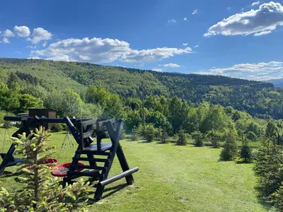 a wooden chair sitting on top of a lush green field at Babia Chata in Zawoja