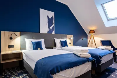 a bedroom with two beds with blue walls at Ilkus Hotel & Restaurant in Krze