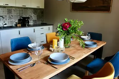 a wooden table with blue plates and a vase of flowers at Garden Loft in Roczyny