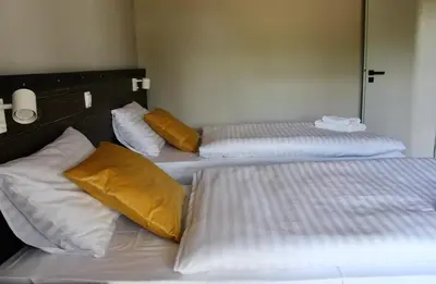 three beds in a room with yellow and white pillows at Garden Loft in Roczyny