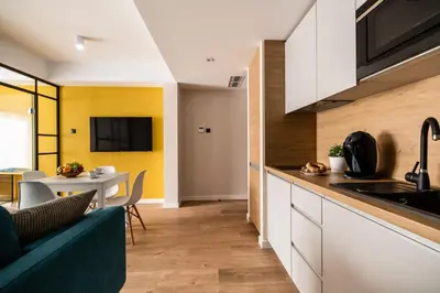 a kitchen with white cabinets and a dining table at Krakow Square Residence in Kraków
