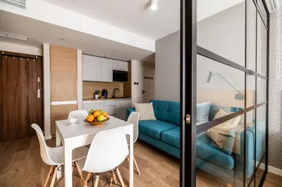 a living room with a table and a blue couch at Krakow Square Residence in Kraków