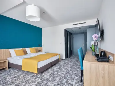 a bedroom with a bed and a blue wall at Tennis & Country Club Hotel in Giebułtów