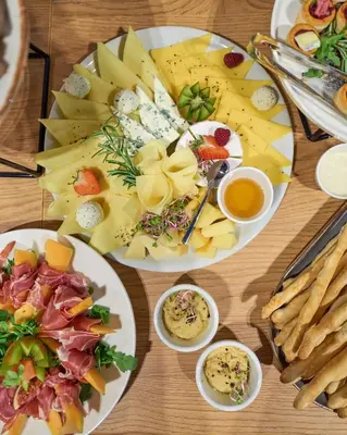 a table topped with plates of cheese and other foods at Tennis & Country Club Hotel in Giebułtów