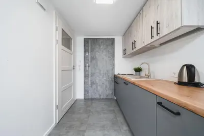 a kitchen with white cabinets and a wooden counter top at Ice Apartments in Kraków