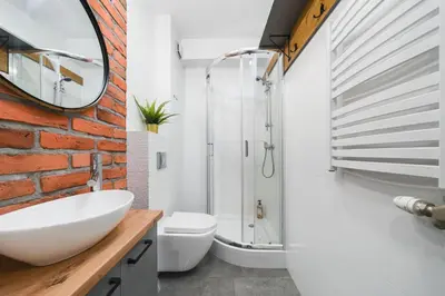 a bathroom with a white sink and a brick wall at Ice Apartments in Kraków