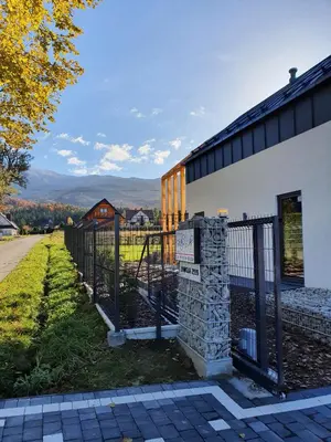 a fence next to a building with mountains in the background at Zawobaja in Zawoja