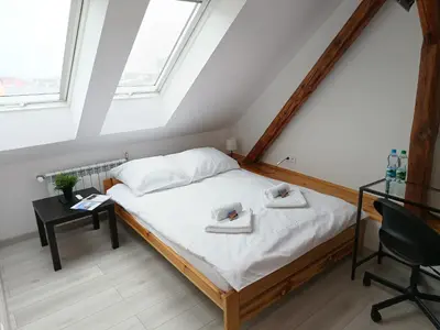 a bedroom with a bed and a desk and windows at Sleep In Center in Kraków