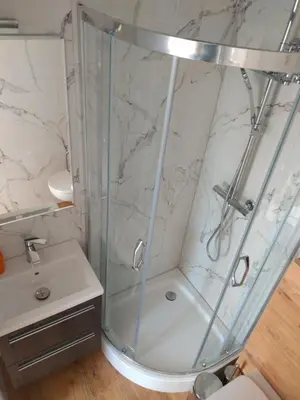 a shower with a glass door next to a sink at Sleep In Center in Kraków