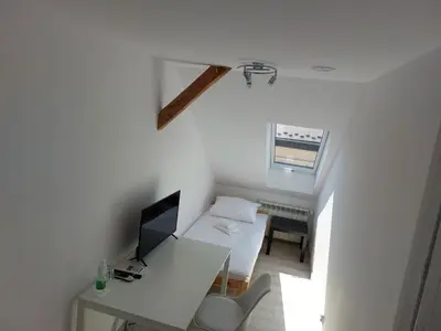 a small white room with a desk and a television at Sleep In Center in Kraków