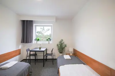 a room with two beds and a table and a window at Hotel pod Wieliczką in Gdów