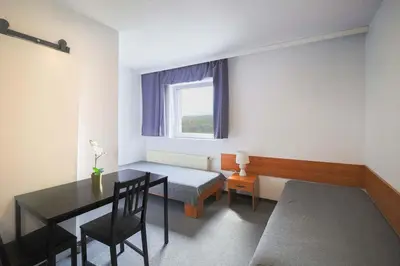 a bedroom with a bed and a table and a window at Hotel pod Wieliczką in Gdów