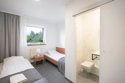 a hotel room with two beds and a toilet at Hotel pod Wieliczką in Gdów